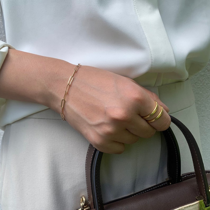 model wearing green dress and link chain bracelet by chokha india carrying a leather bag 