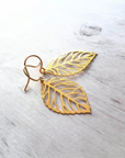 gold plated leaf shaped earrings which are made of 92.5 sterling silver by chokha india kept side by side