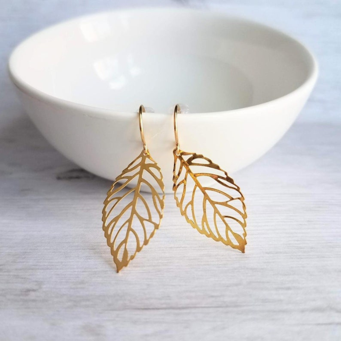 gold plated leaf shaped earrings which are made of 92.5 sterling silver by chokha india hanging by a cup 