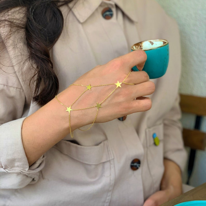 model sipping coffee wearing star charm hand chain 